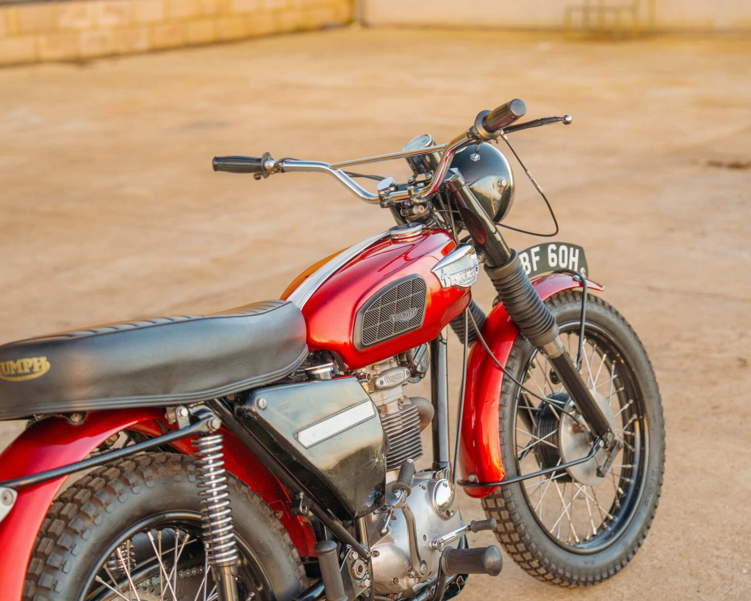 Vintage Triumph motorcycle with red and black paint, classic design, and retro features.