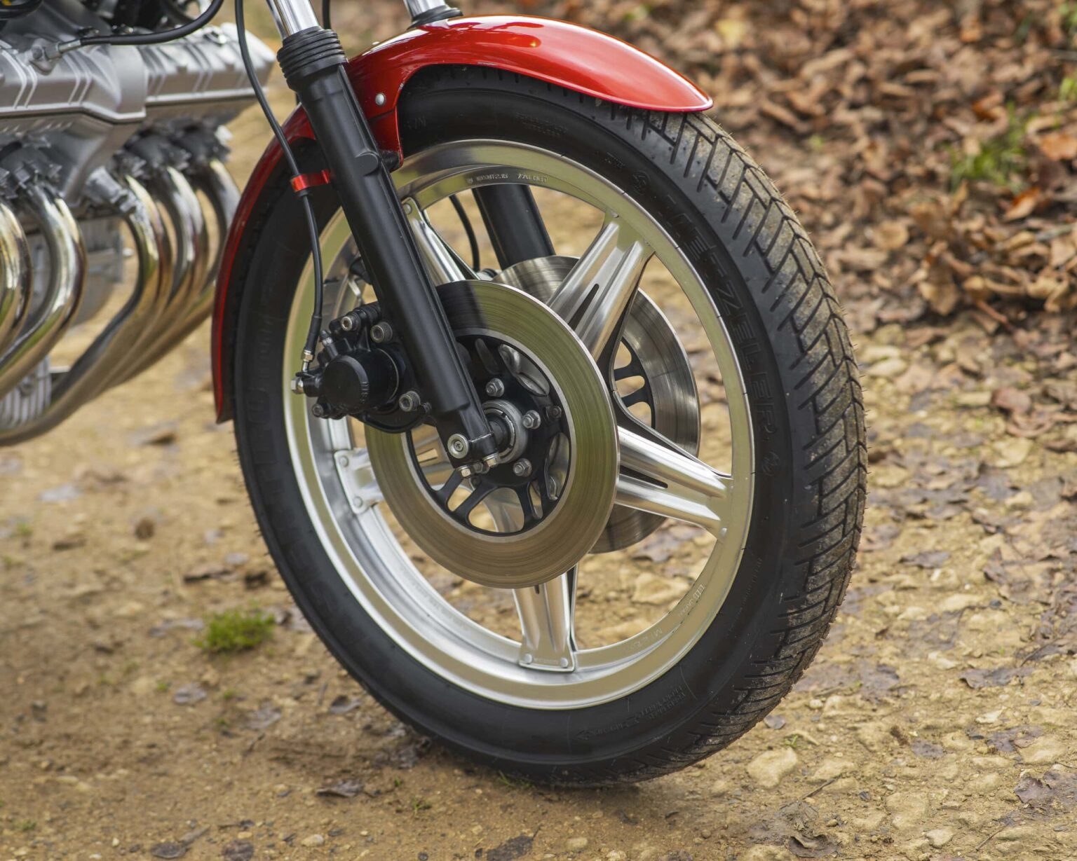 Motorcycle front wheel with disc brake and red fender.