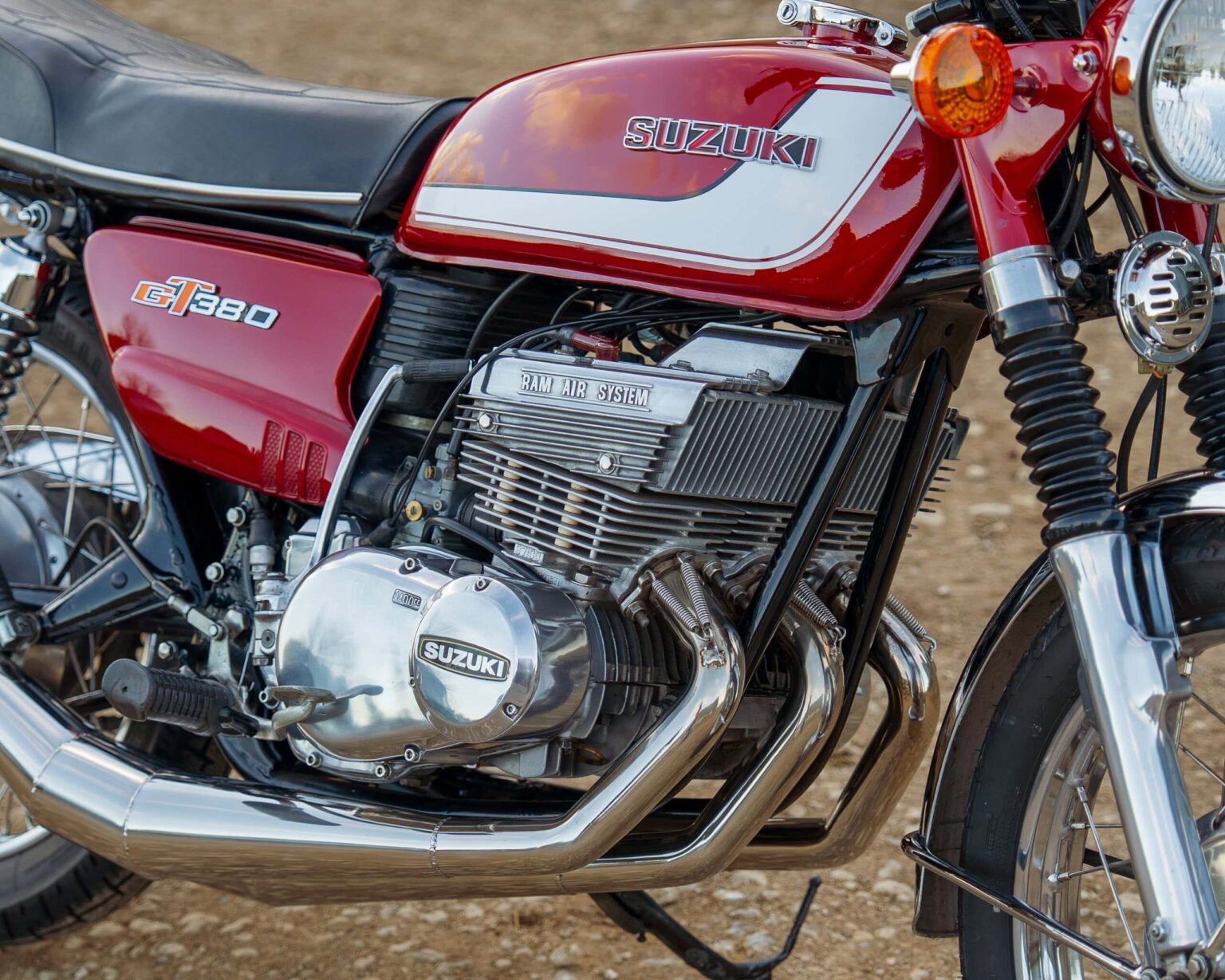 Vintage Suzuki GT380 motorcycle showcasing classic red and silver colour scheme and detailed engine parts.