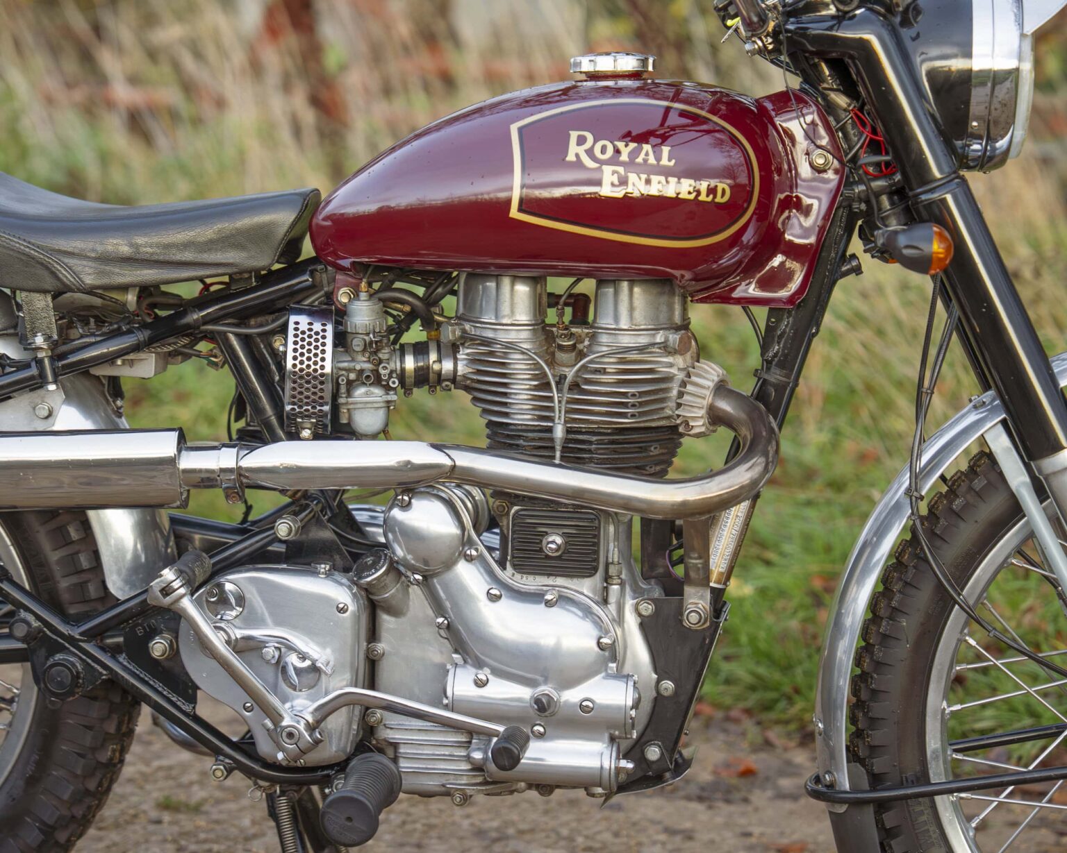 Classic Royal Enfield motorcycle with a maroon fuel tank and vintage design.