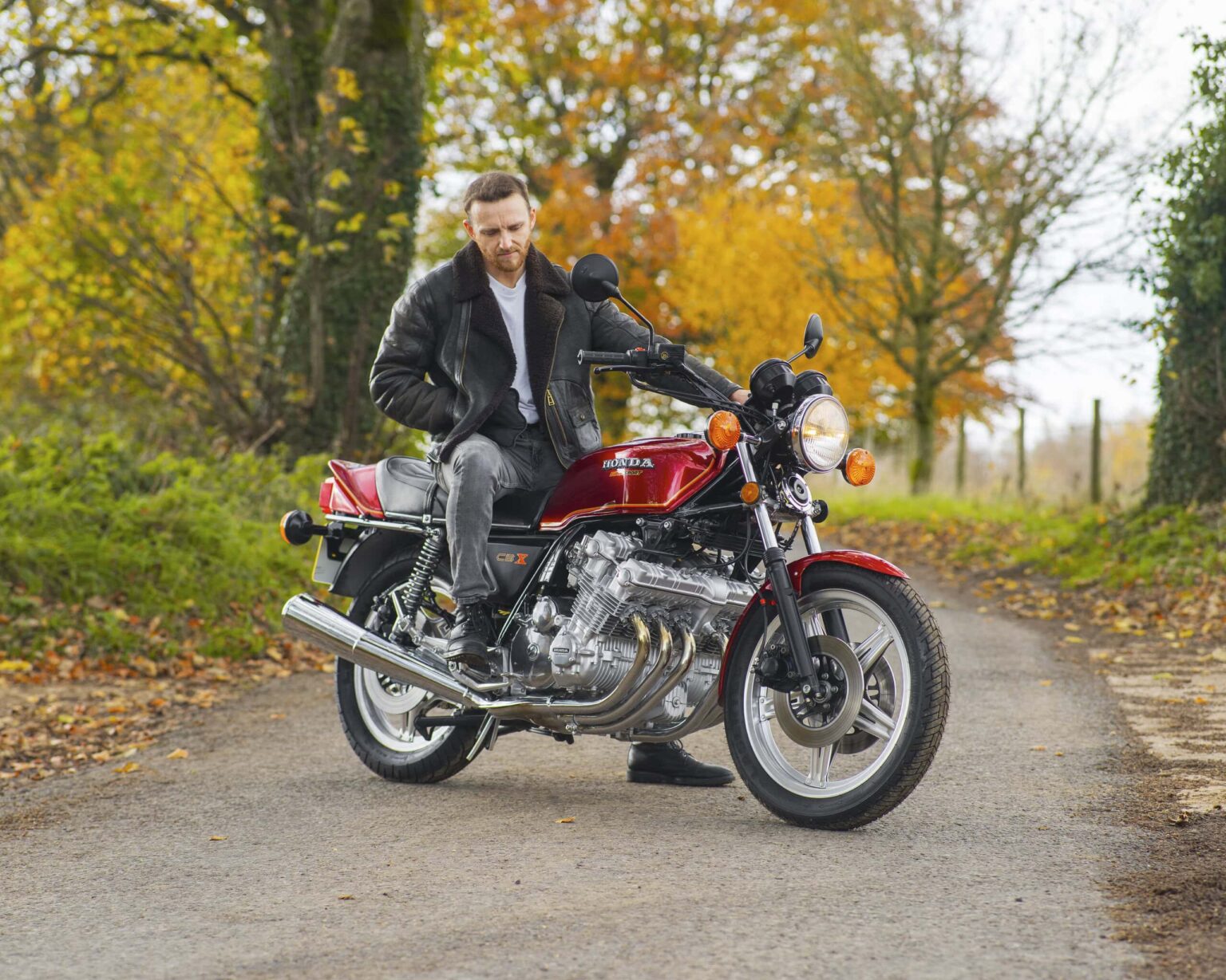 Motorcycle parked on a scenic autumn forest road with colourful fall foliage.