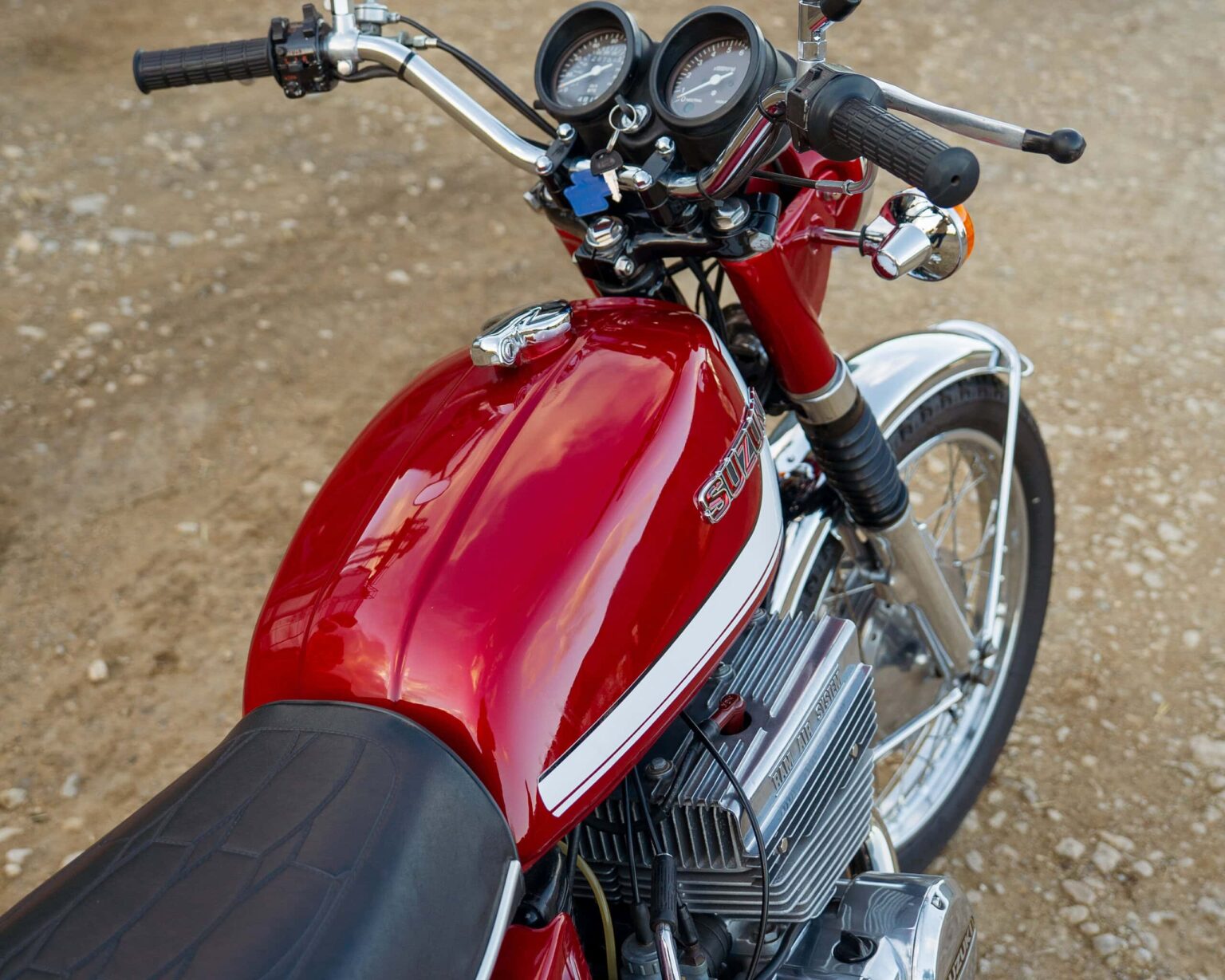 Close-up of vintage red Suzuki racing motorcycle with detailed fuel tank and controls.