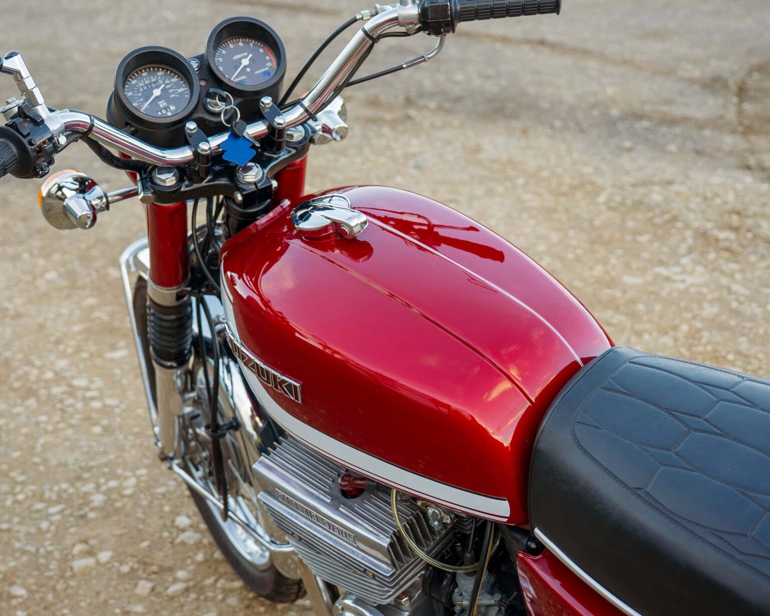 Red vintage Suzuki motorcycle on gravel.