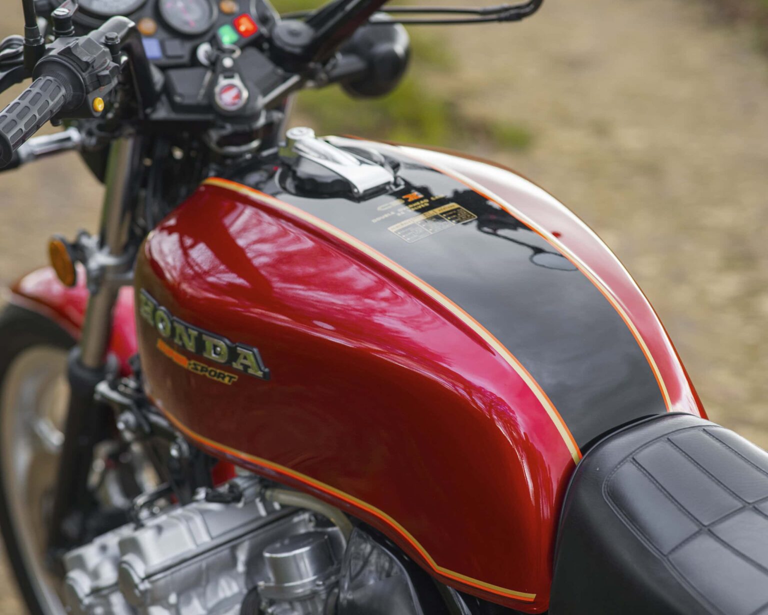 Motorcycle fuel tank with Honda logo and red, black, and gold design.