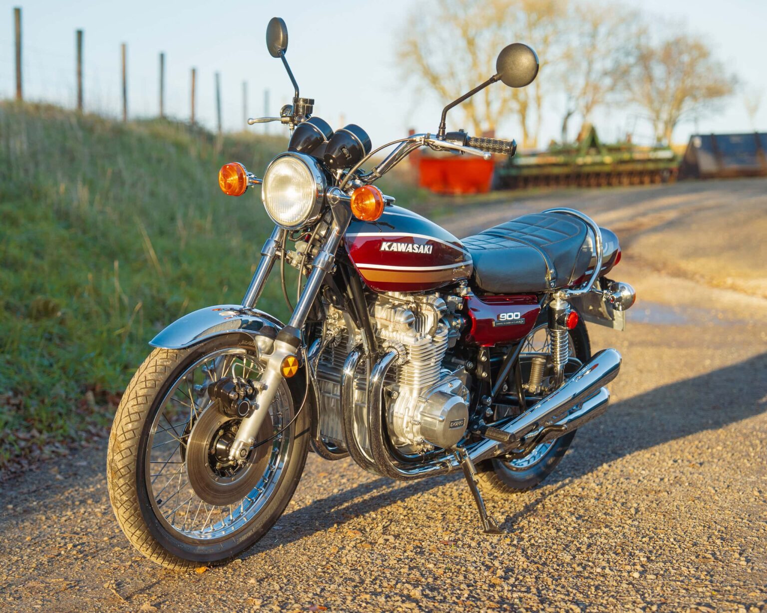 Vintage Kawasaki motorcycle, classic bike on rural road with open landscape and sunset lighting.