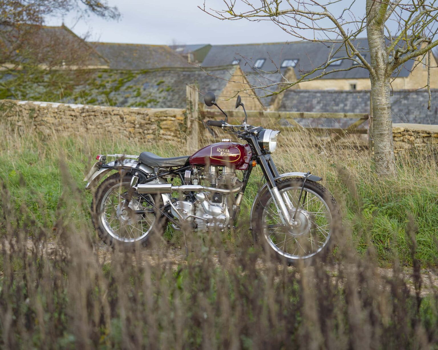 Vintage motorcycle parked in a rural landscape with grass and trees.