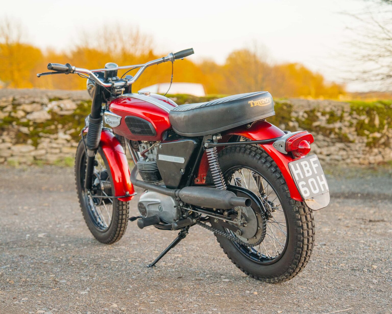 Vintage red motorcycle parked outdoors with a scenic background.
