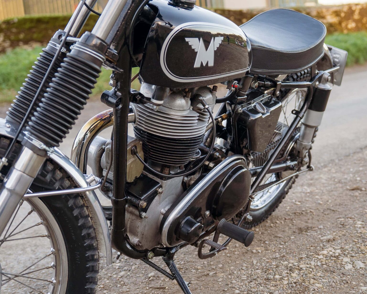 Close-up of a classic black vintage motorcycle with silver engine components and knobby tires, showcasing retro style and craftsmanship.
