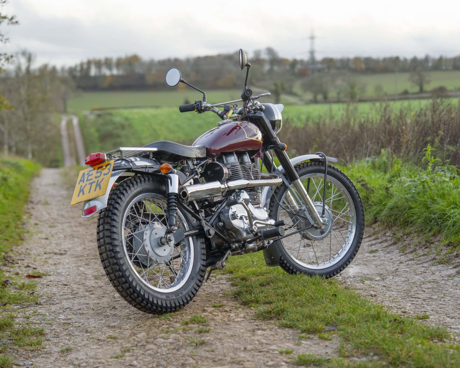 Vintage motorcycle parked on a dirt track in the countryside.