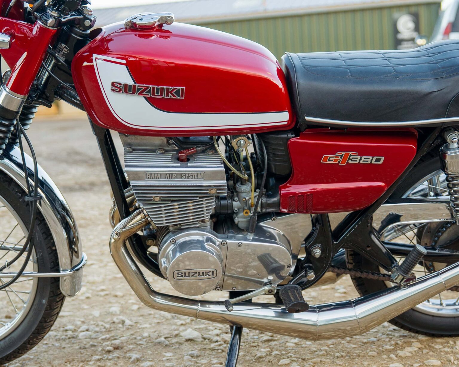 Close-up of vintage Suzuki GT380 motorcycle engine and red fuel tank with logo.