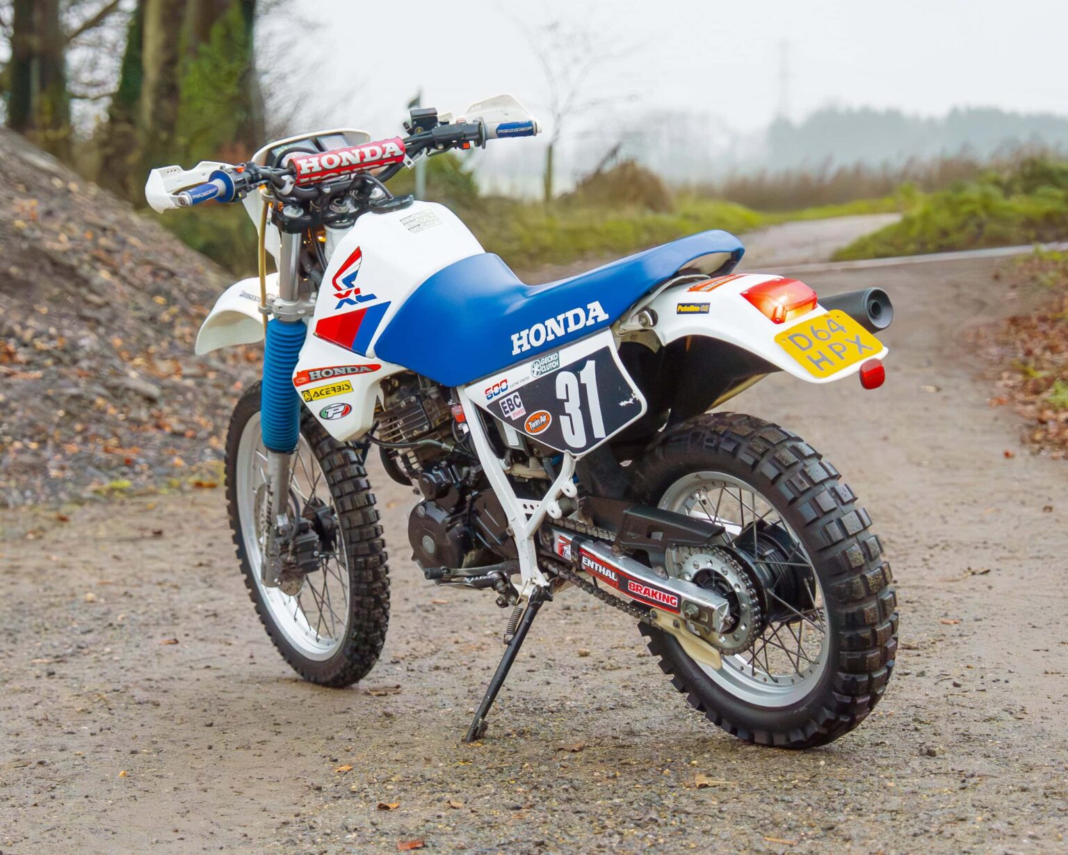 Classic Honda off-road motorcycle on a dirt trail, ready for competition.