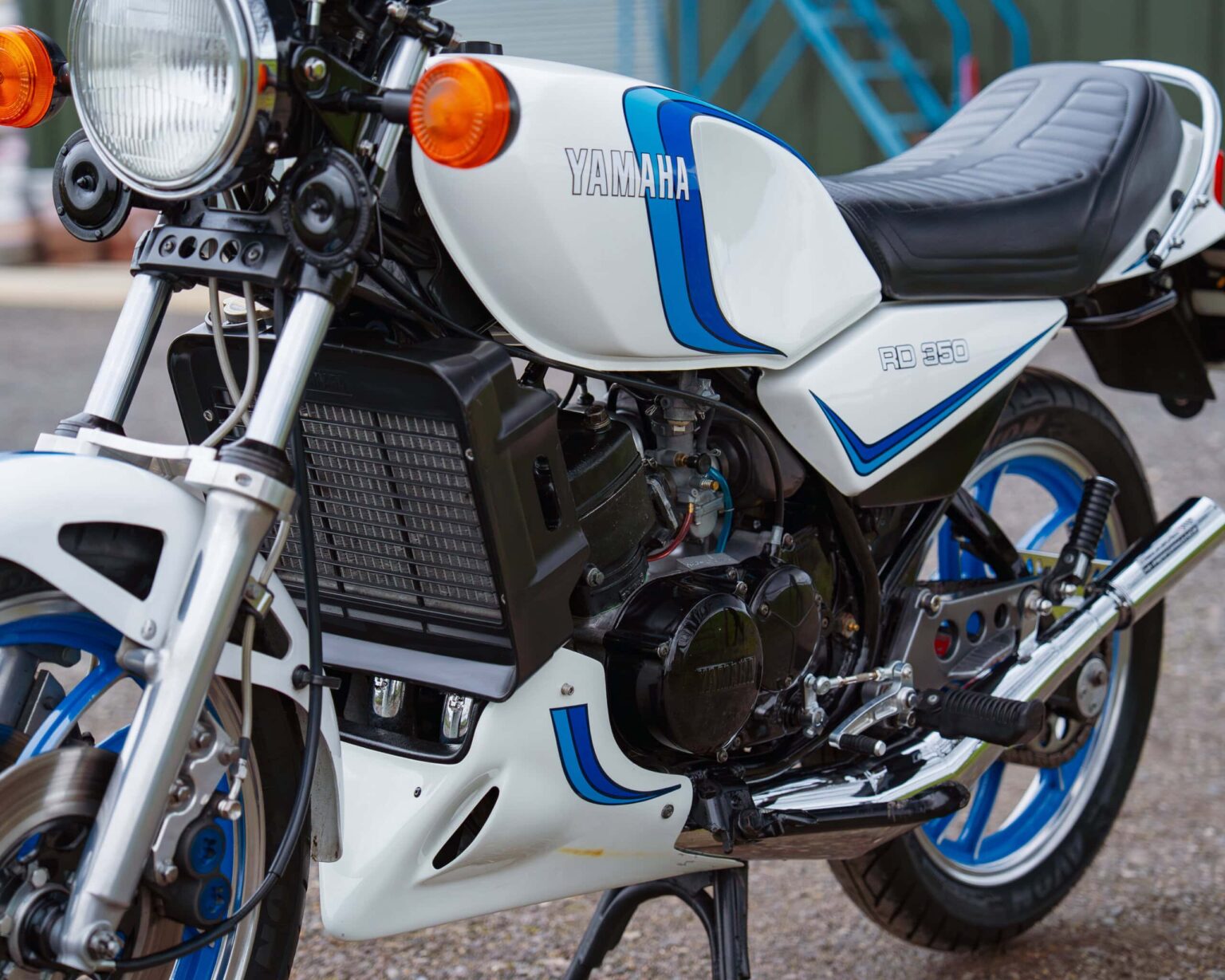 Detailed view of Yamaha RD 350, vintage sport bike with white and blue livery, black engine, and classic design.