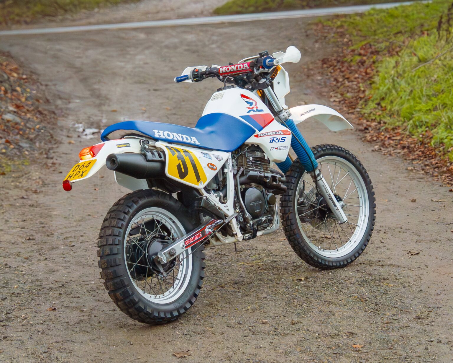 Off-road Honda CRF dirt bike on a gravel trail with autumn foliage.