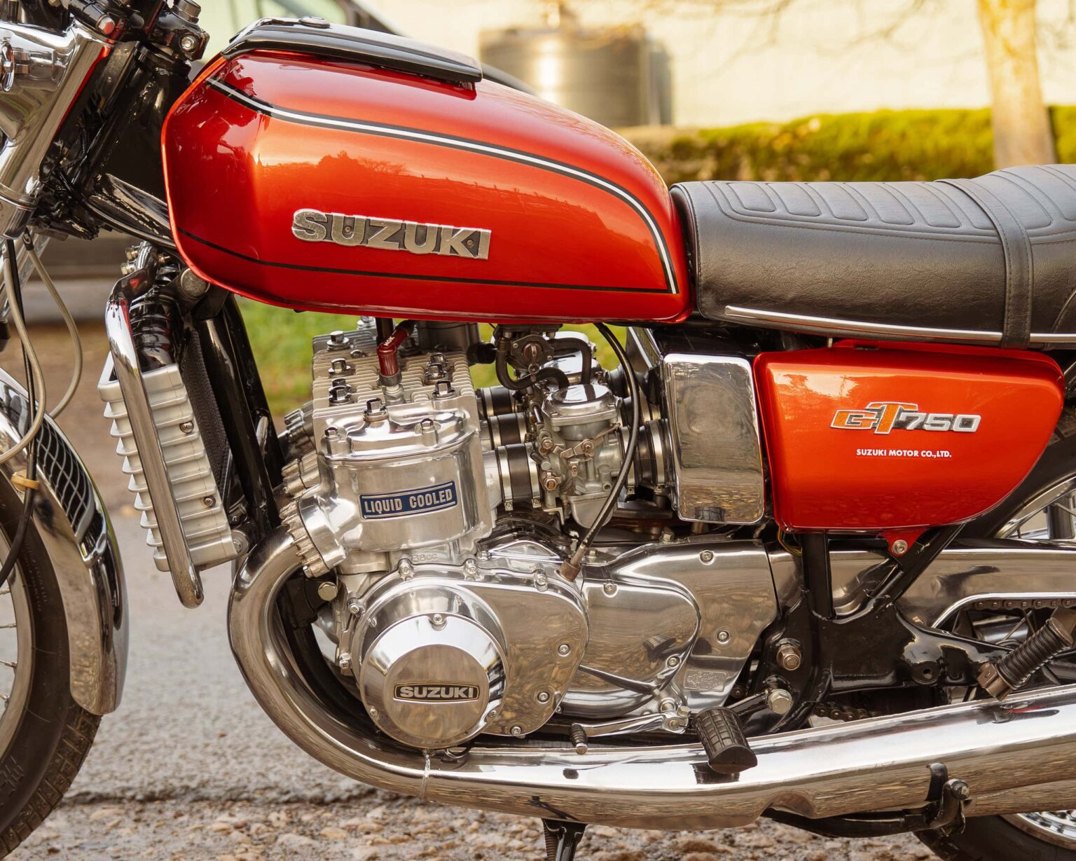 High-resolution image of a vintage Suzuki motorcycle's engine and red fuel tank, highlighting classic motorbike details.