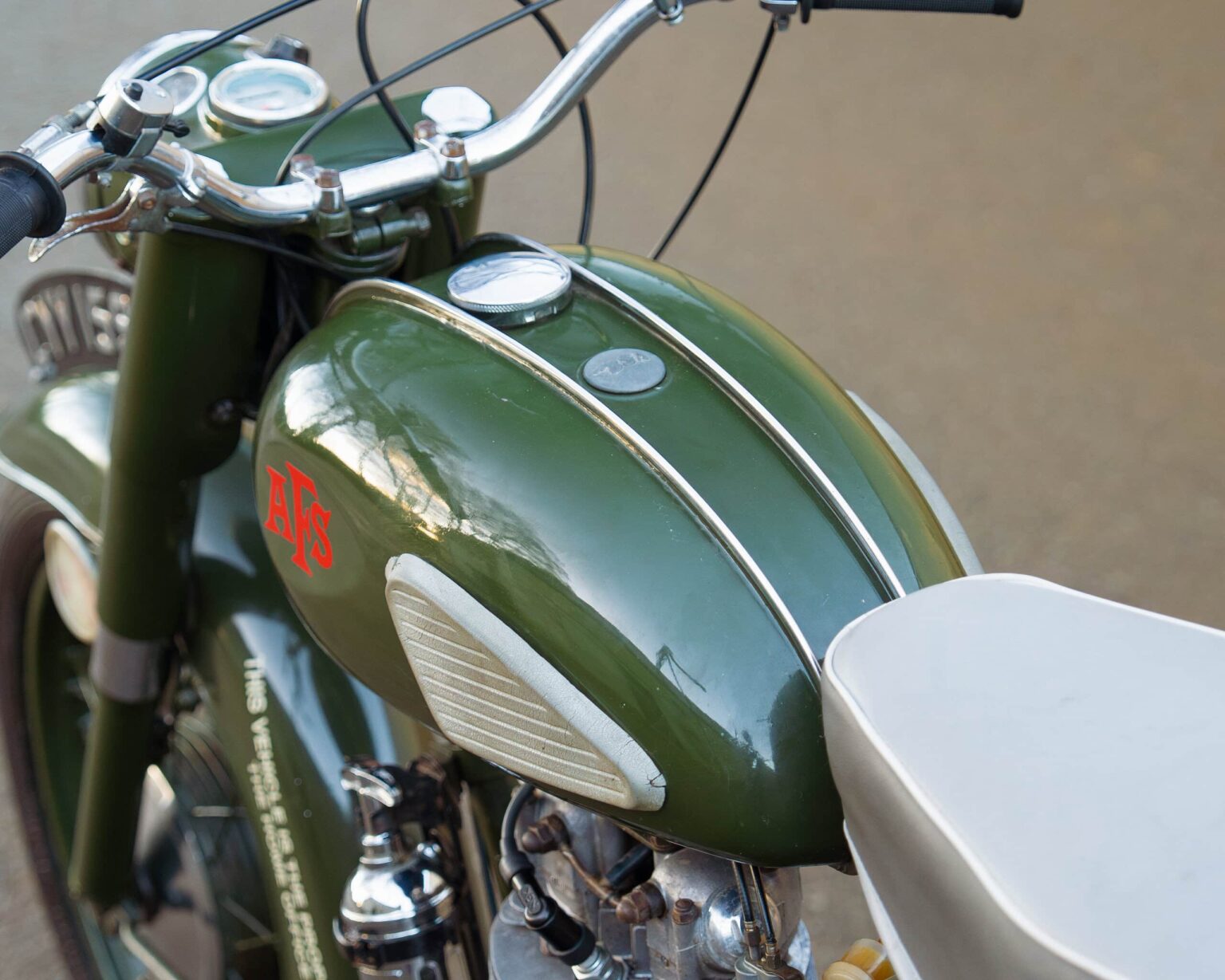 Vintage green motorcycle with chrome accents and a white seat, showcasing classic design.