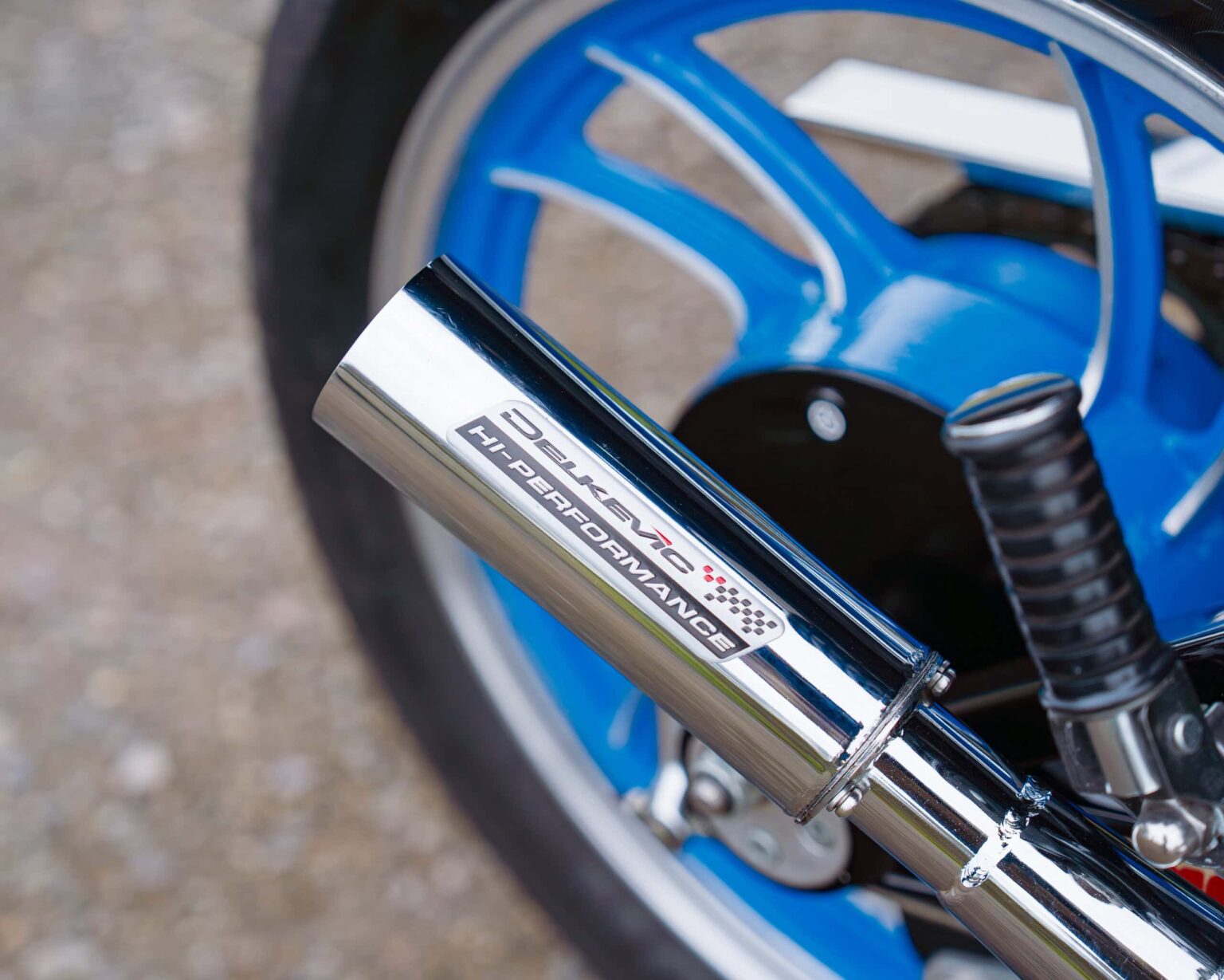 Close-up of a high-performance Deleney Hi-Performance exhaust on a vintage sports car.