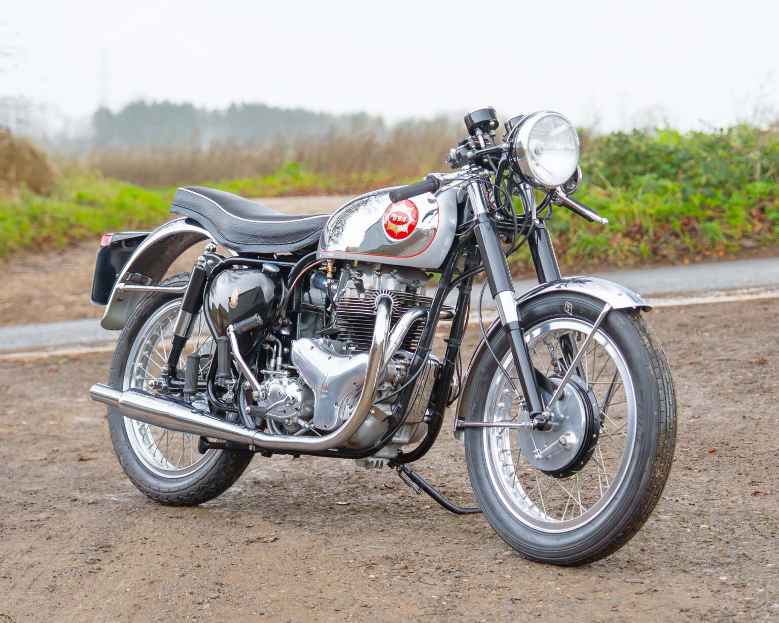 Classic black and silver vintage model with detailed engine and exhaust, set outdoors for a race or show.