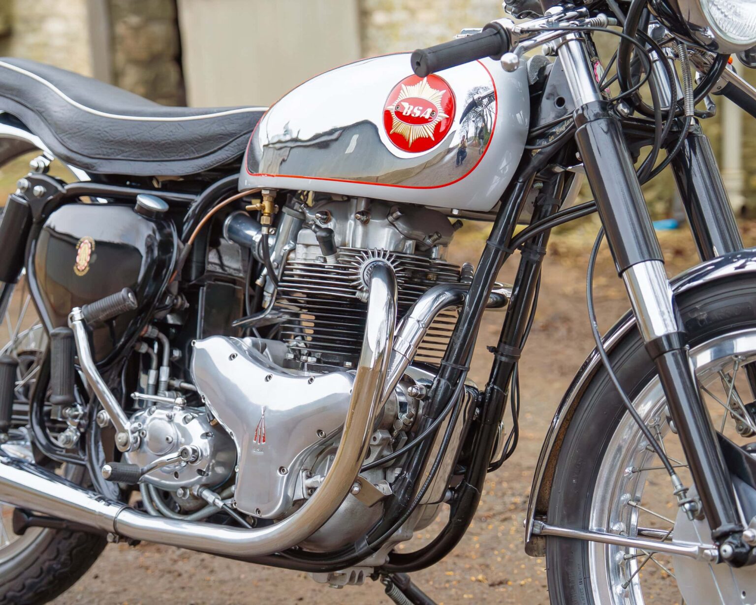 Classic motorcycle engine with vintage design and polished chrome, displayed outdoors at a vintage bike show.