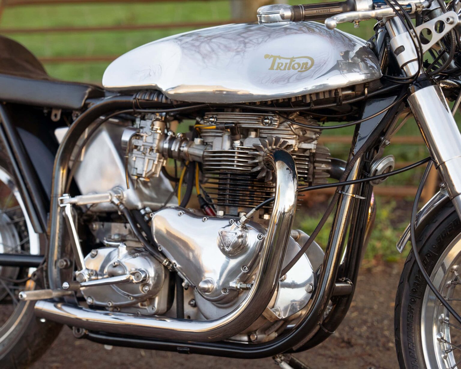 A vintage Triumph Triton motorcycle engine on display outdoors.