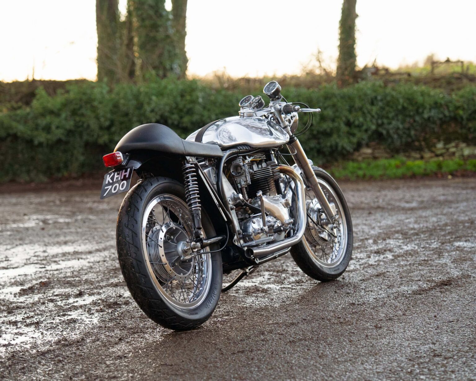 Vintage motorcycle with polished metal and black accents, park at outdoor event.