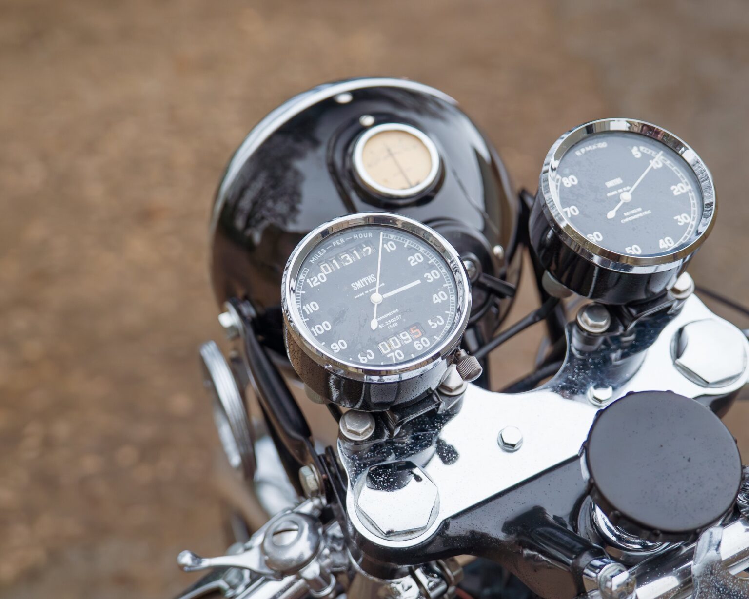 Close-up of vintage motorcycle speedometer and tachometer showing speed and distance.