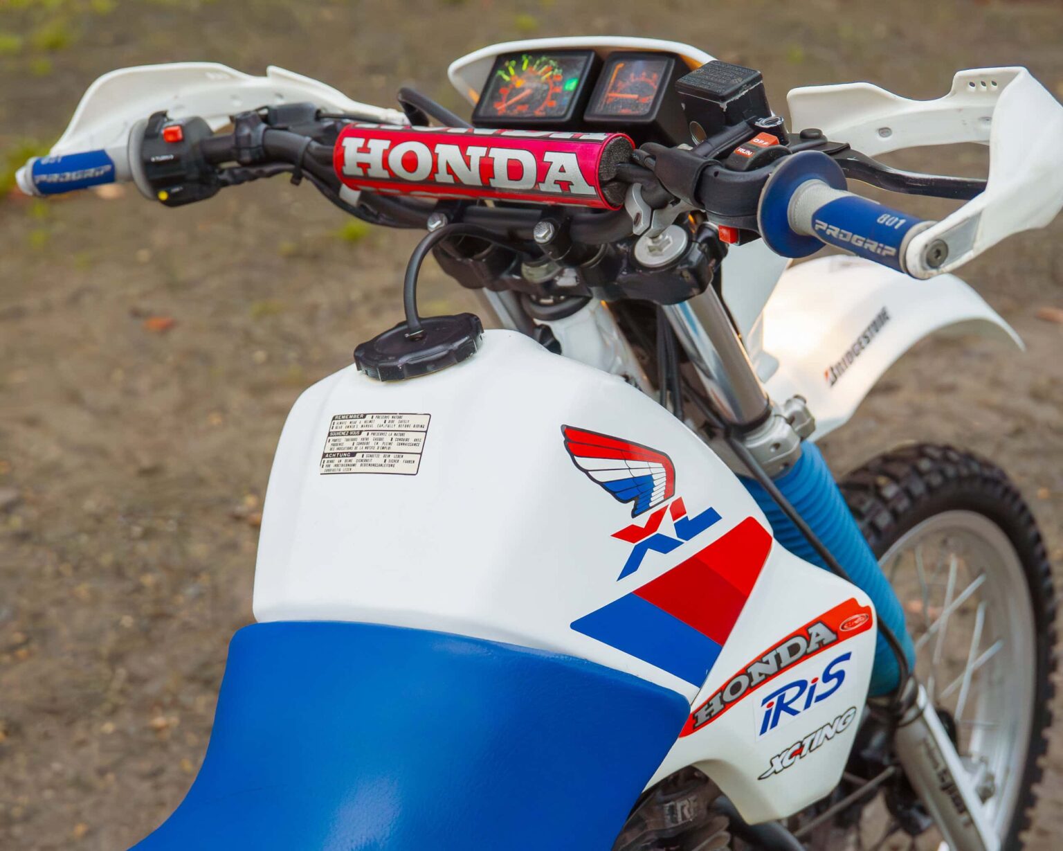 Dirt bike with Honda branding, digital dashboard, and rugged tyres.