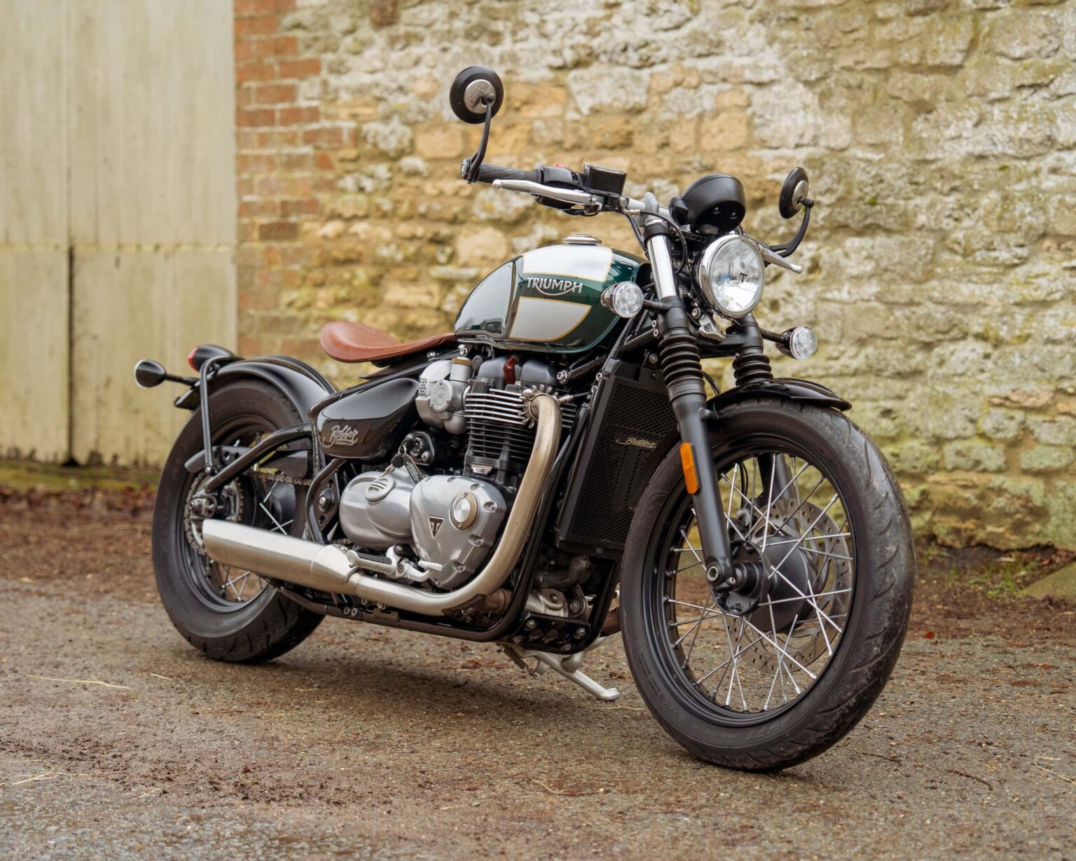Triumph motorcycle parked outdoors against a brick wall.