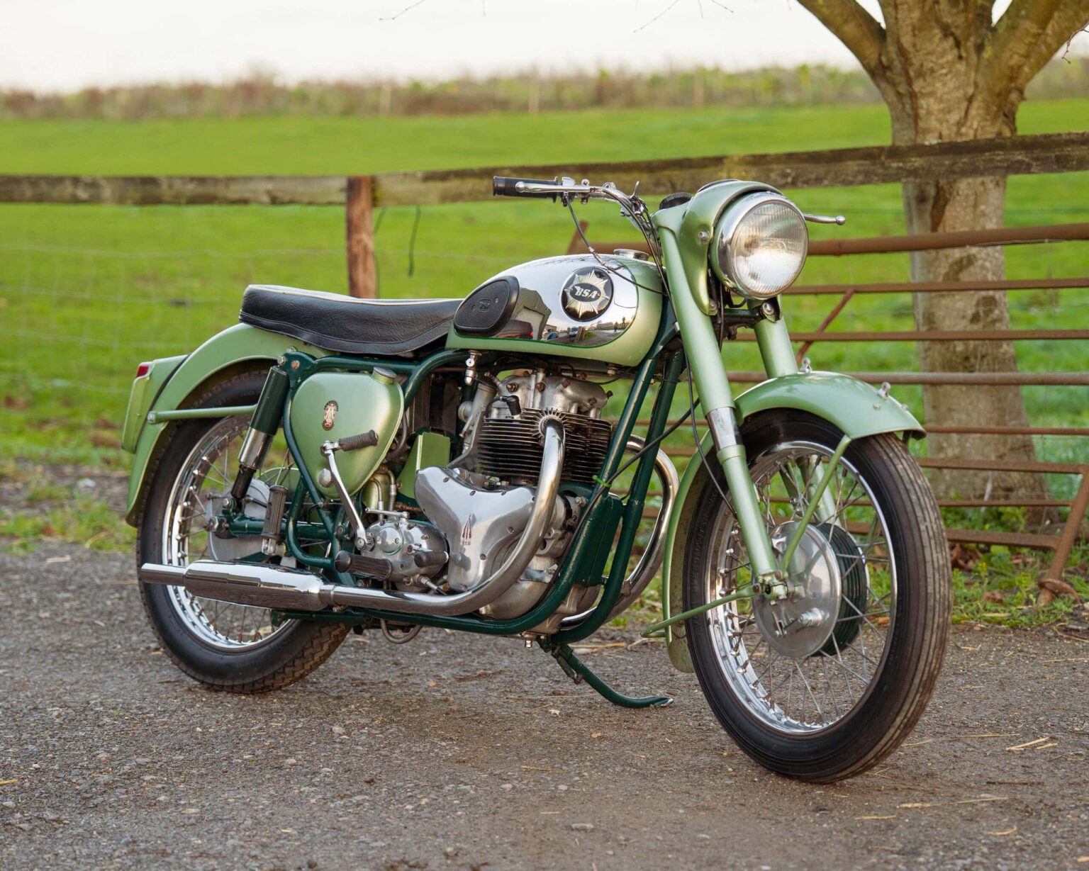 Classic motorcycle in green and chrome parked outdoors.