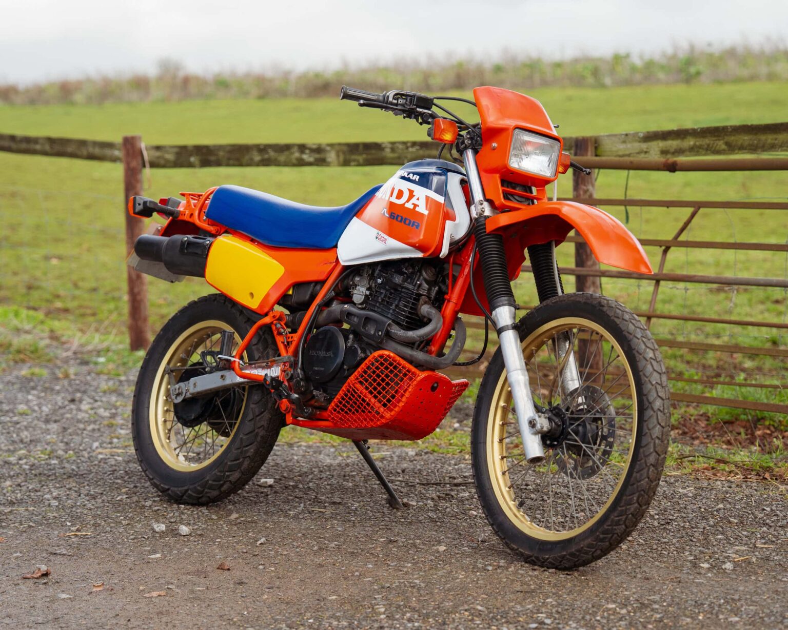 Vintage orange and blue off-road motorcycle with racing decals.