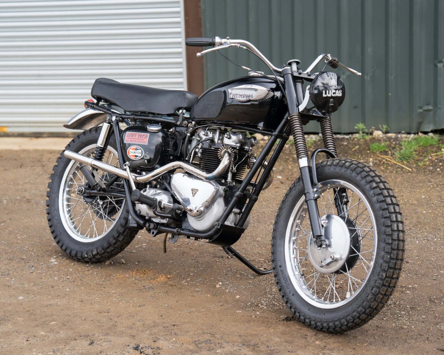 Vintage Triumph motorcycle with off-road tyres and racing modifications.