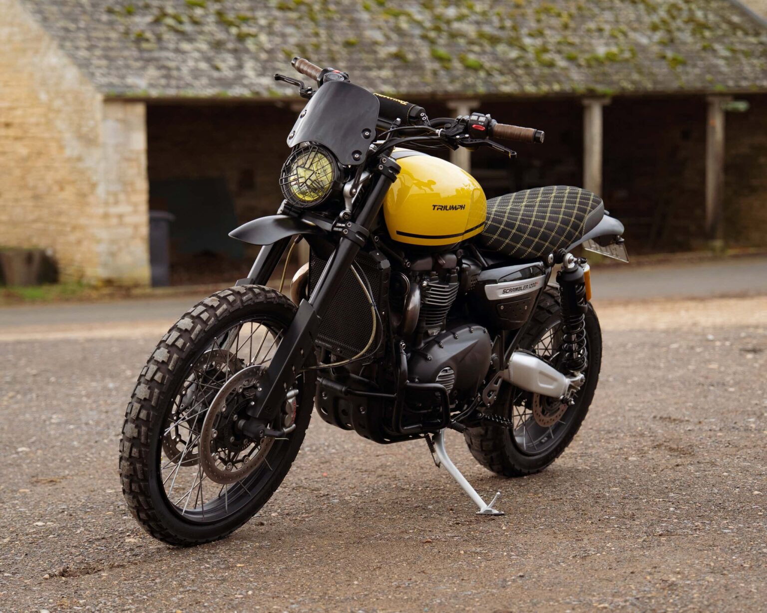Motorcycle with yellow fuel tank and black accents, parked outdoors.