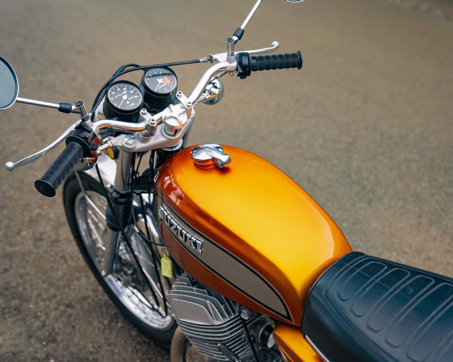 Motorcycle with orange fuel tank and vintage design.