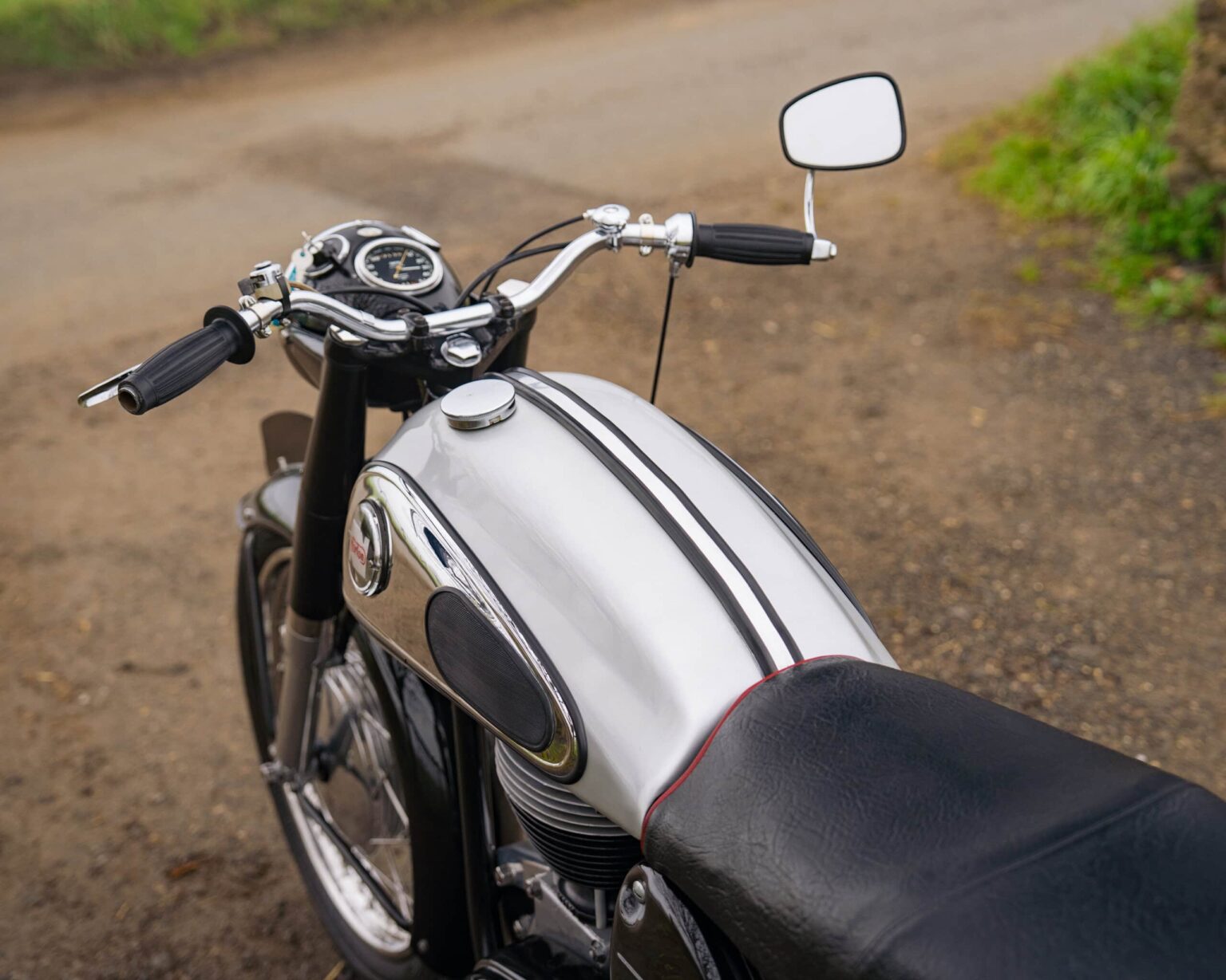 Vintage motorcycle with black and silver finish on a gravel path.