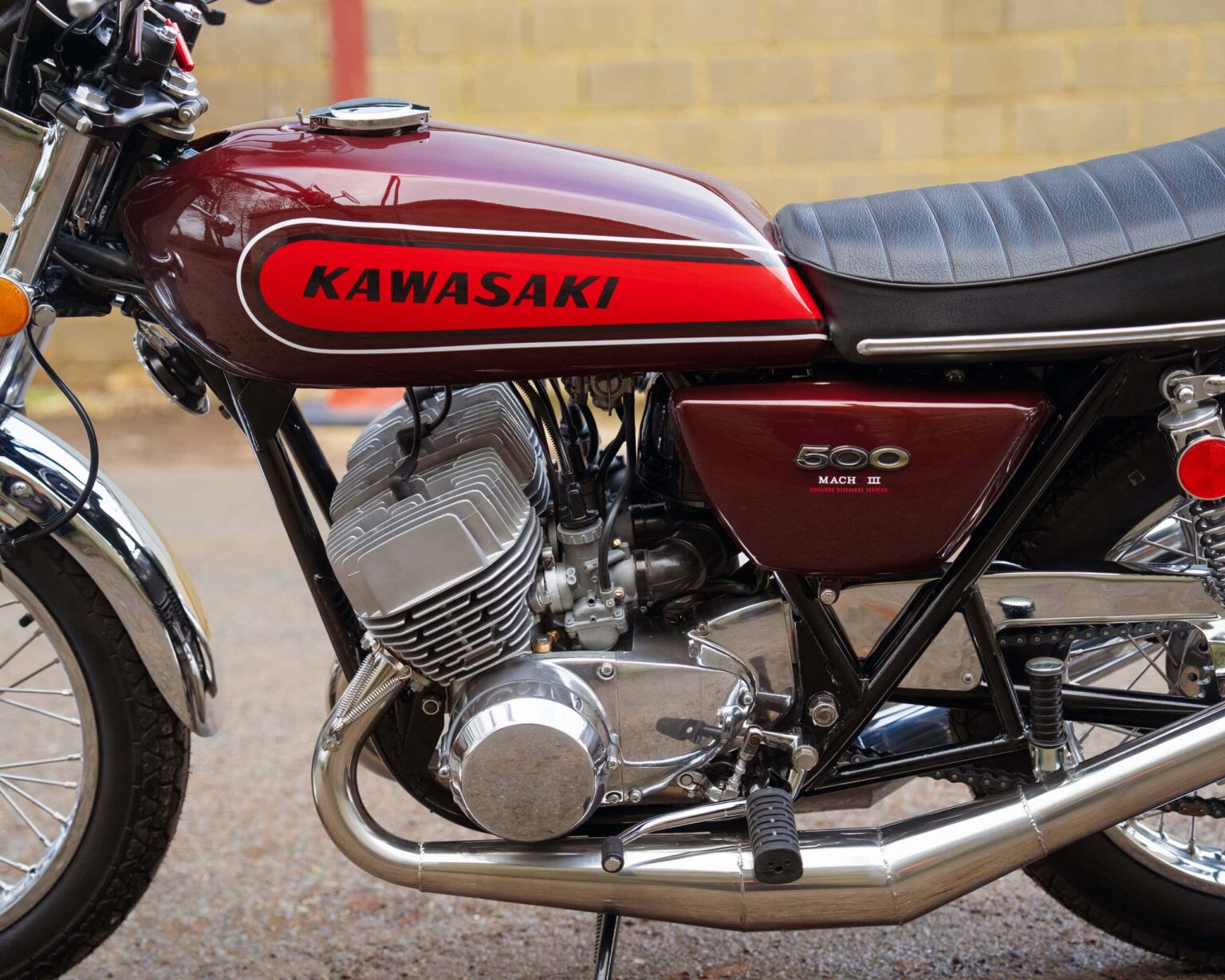 Kawasaki 500 Mach 1 vintage motorcycle with red fuel tank and black seat. Classic design, detailed e.