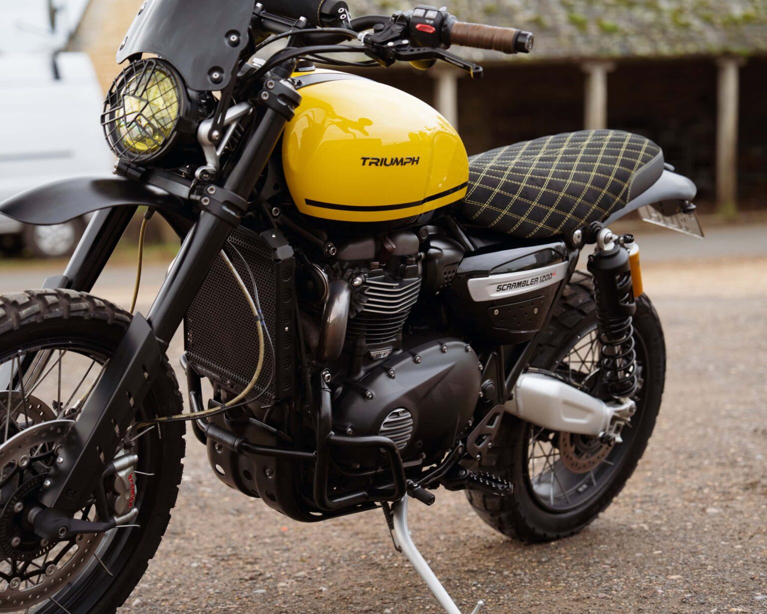 Triumph Scrambler motorcycle with a yellow fuel tank and black frame.