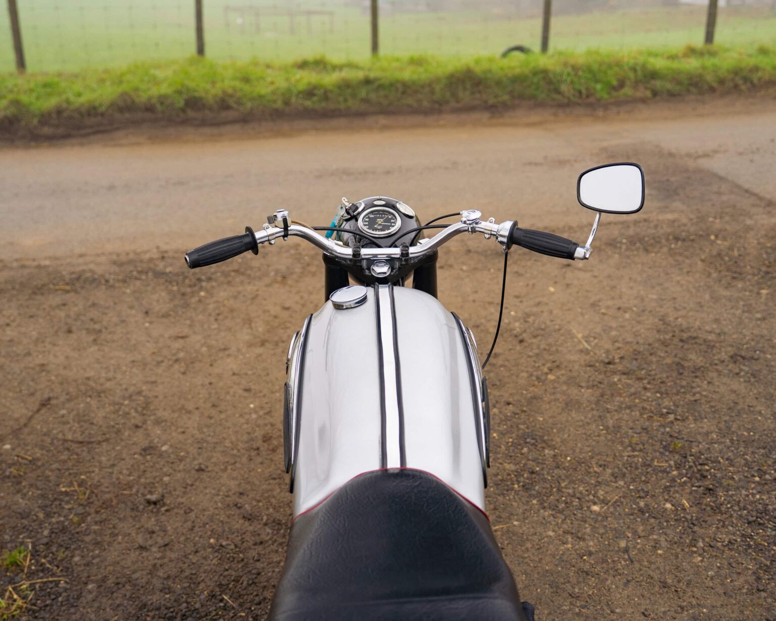 Motorcycle viewed from the rider's perspective, showing handlebars and fuel tank.