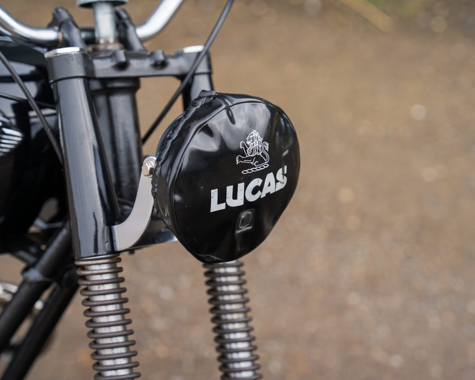 Close-up of a motorcycle with a Lucas branded component on the front suspension.