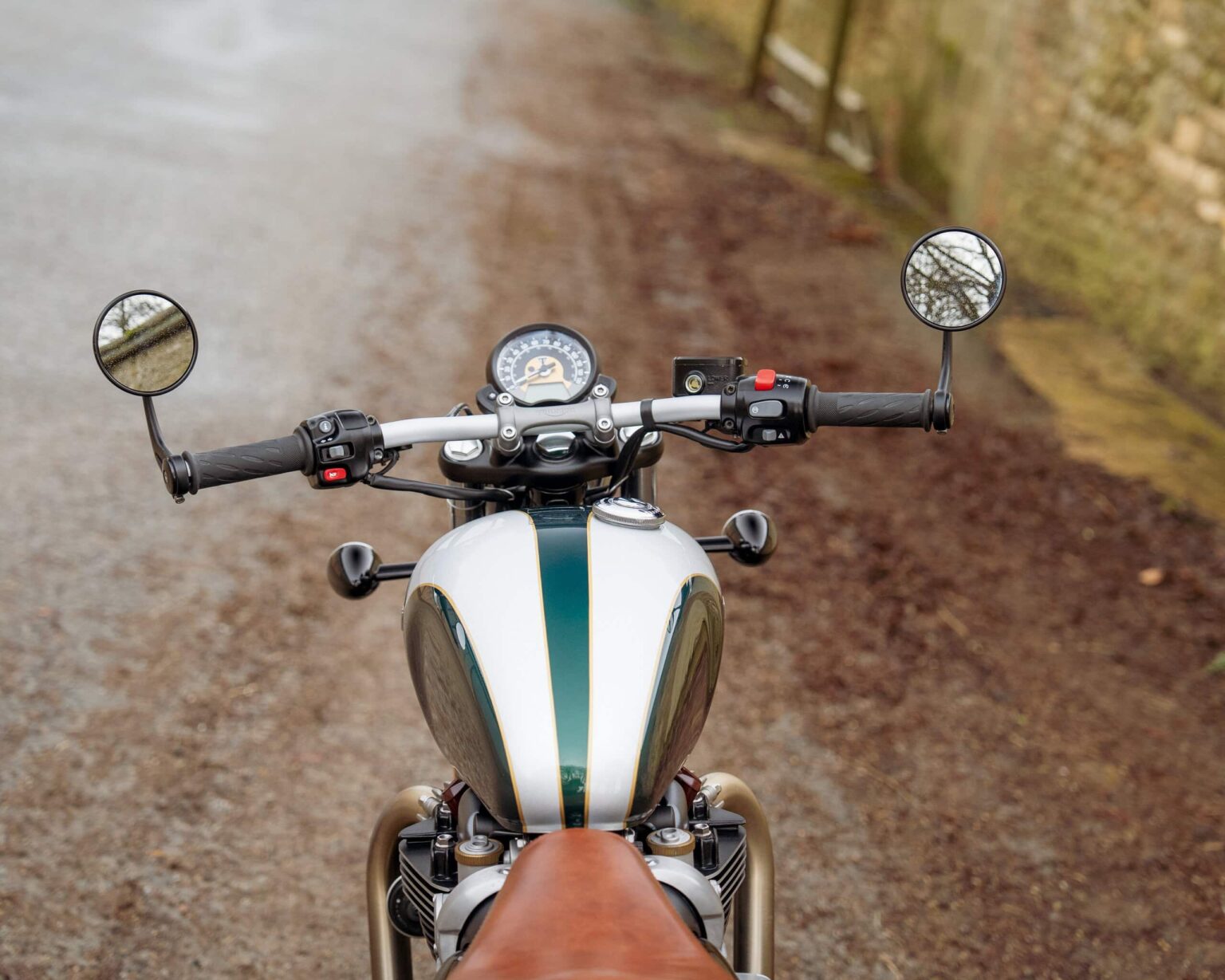 Motorcycle viewed from the rider's perspective on a gravel path.