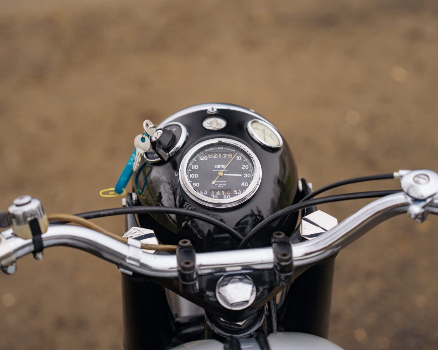 Vintage motorcycle dashboard with speedometer and handlebars.