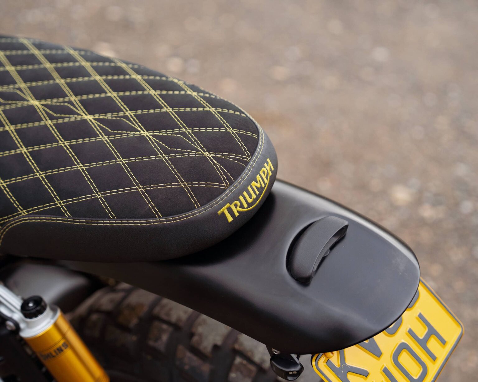 Motorcycle seat featuring Triumph logo and detailed stitching.