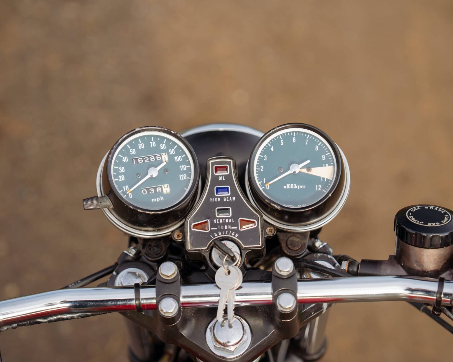 Close-up of a vintage motorcycle speedometer and tachometer.