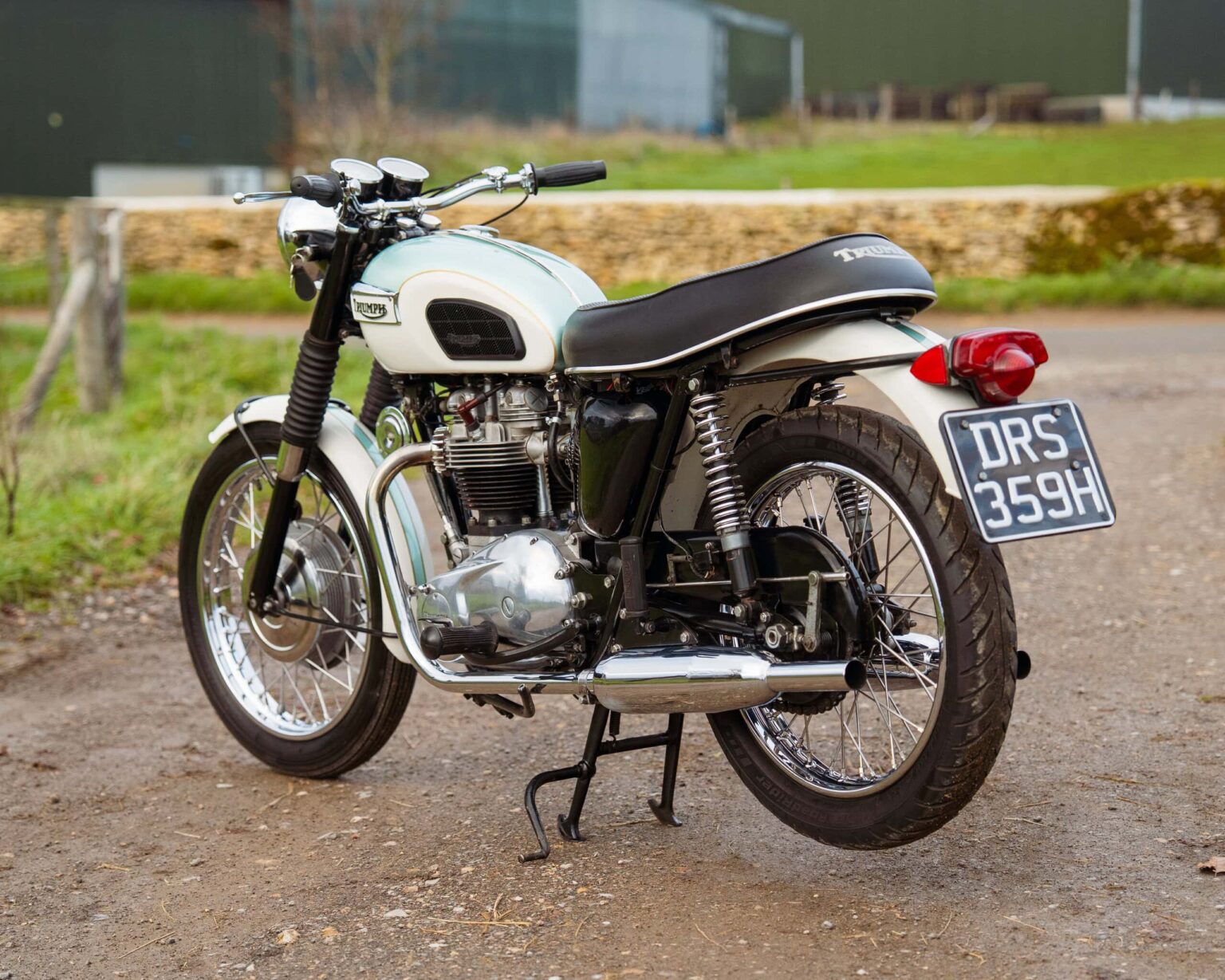 Vintage motorcycle with black and white colour scheme, parked outdoors on a gravel surface.