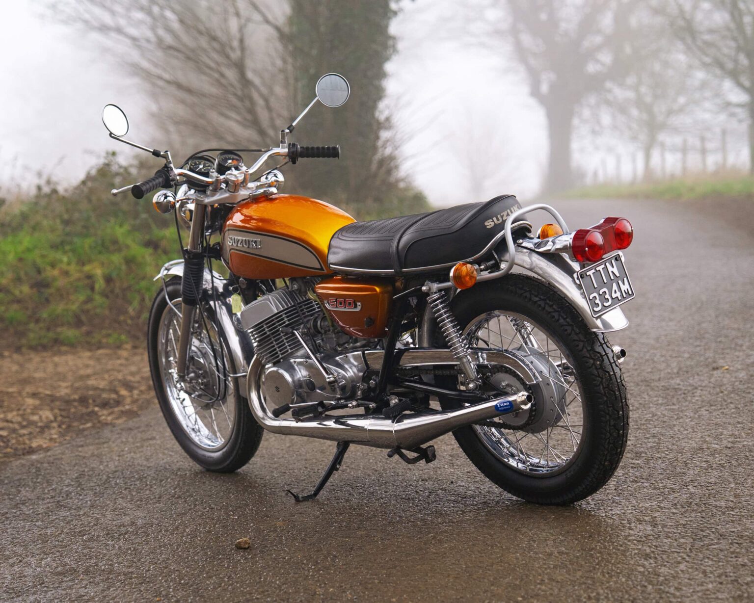 Suzuki vintage motorcycle parked on a country road with foggy background.