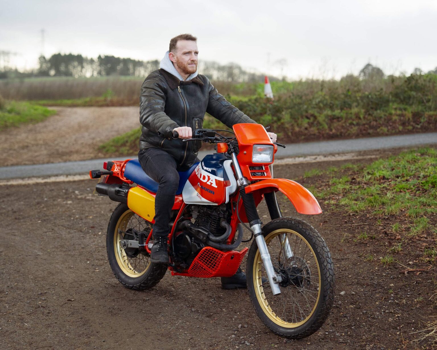Honda dirt bike rider on a vintage motorcycle at a motorsport event.