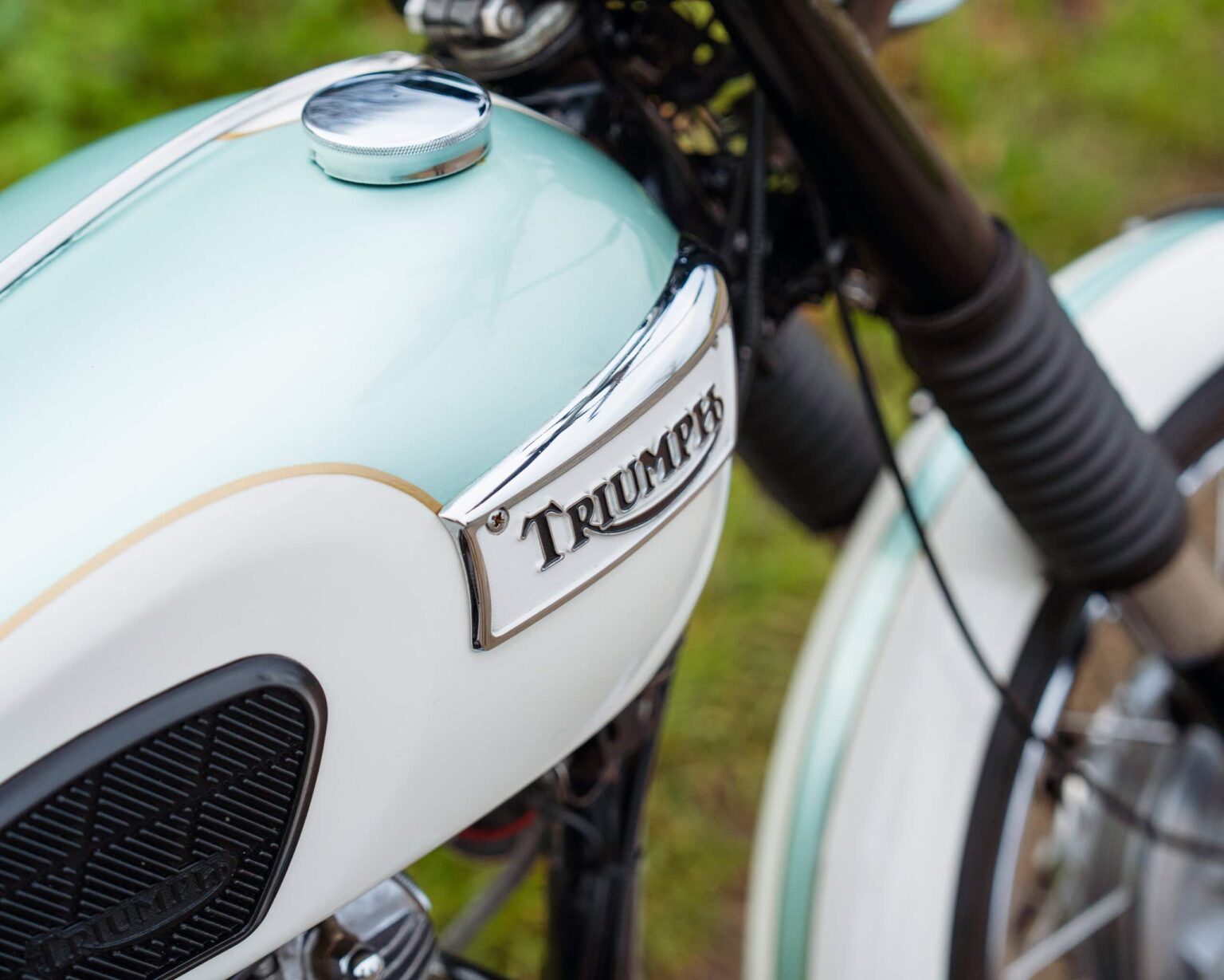 Close-up of a vintage Triumph motorcycle fuel tank with logo.