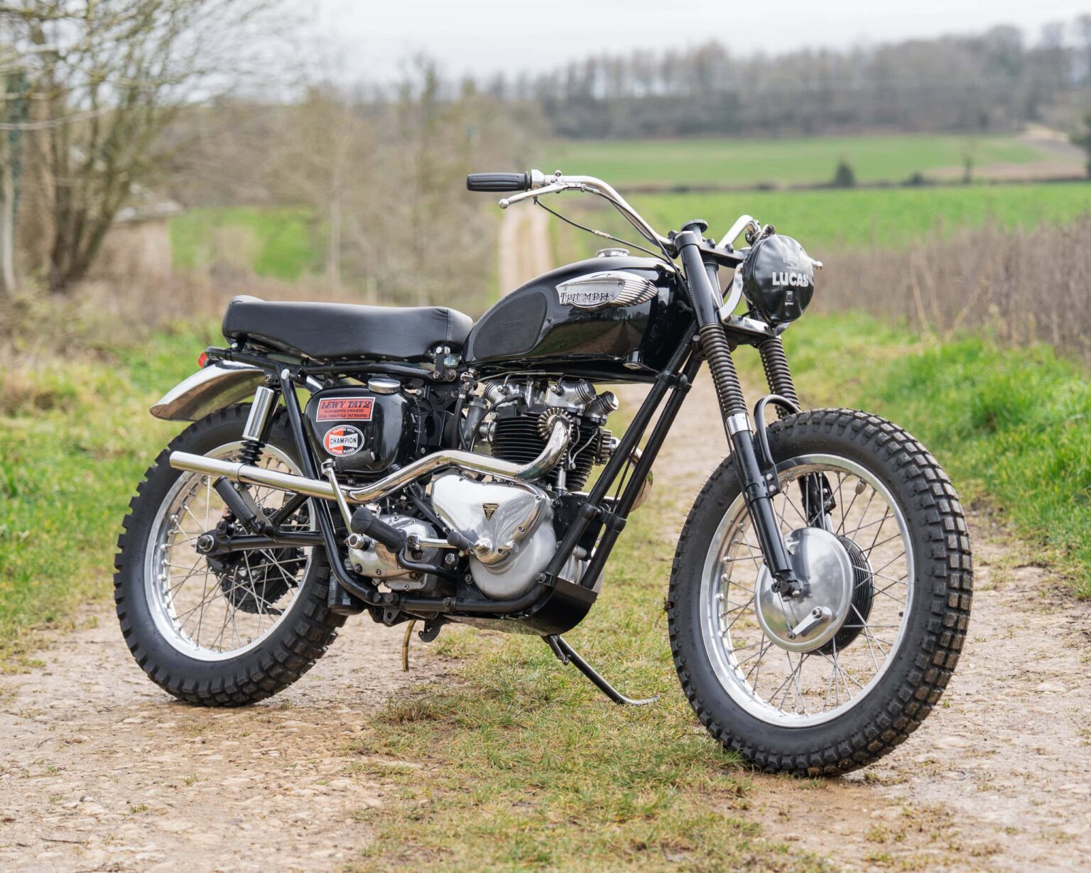 Vintage black motorcycle on a rural dirt path.