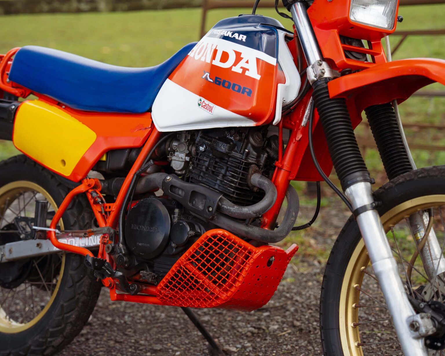 Honda dirt bike with red, white, and blue colour scheme, off-road motorcycle for racing.