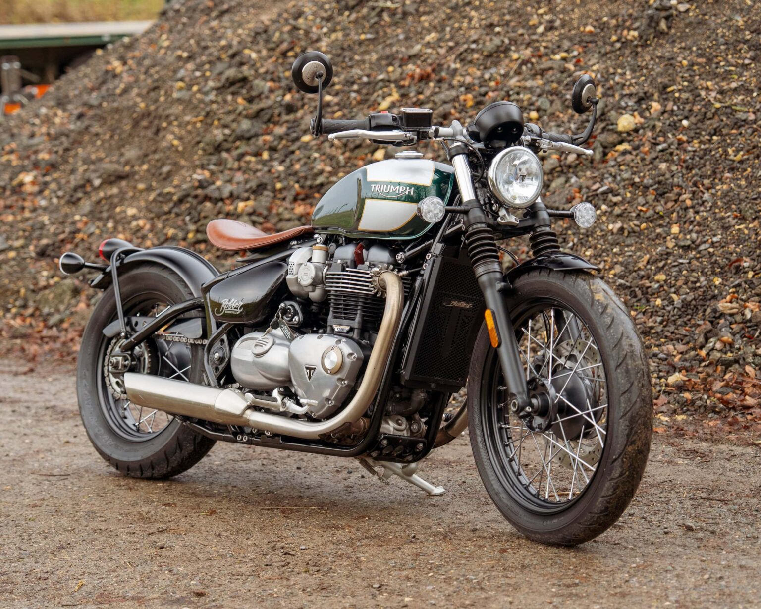 Classic Triumph Bonneville motorcycle parked outdoors on gravel.