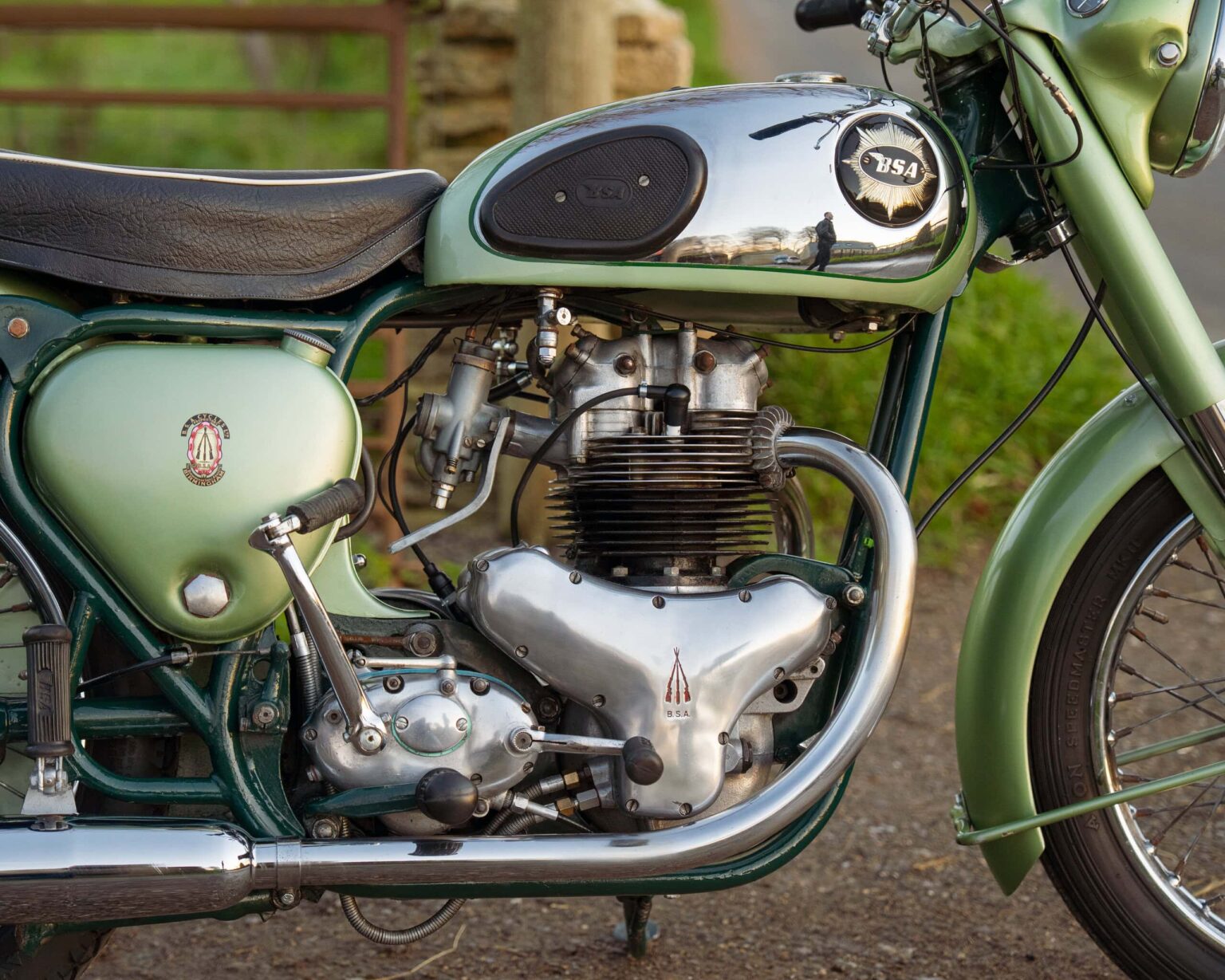 Vintage motorcycle with classic design and green colour, displayed outdoors.