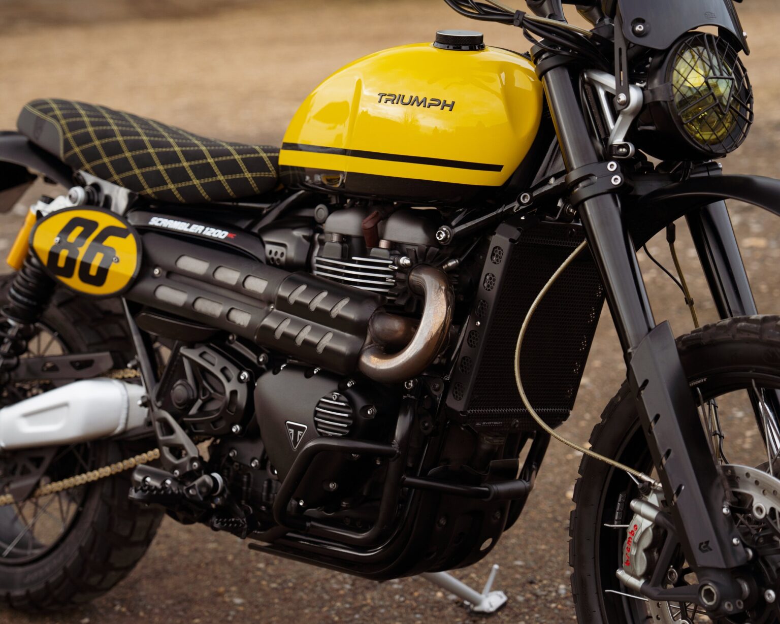 Yellow Triumph motorcycle with racing number 86 on a dirt track.